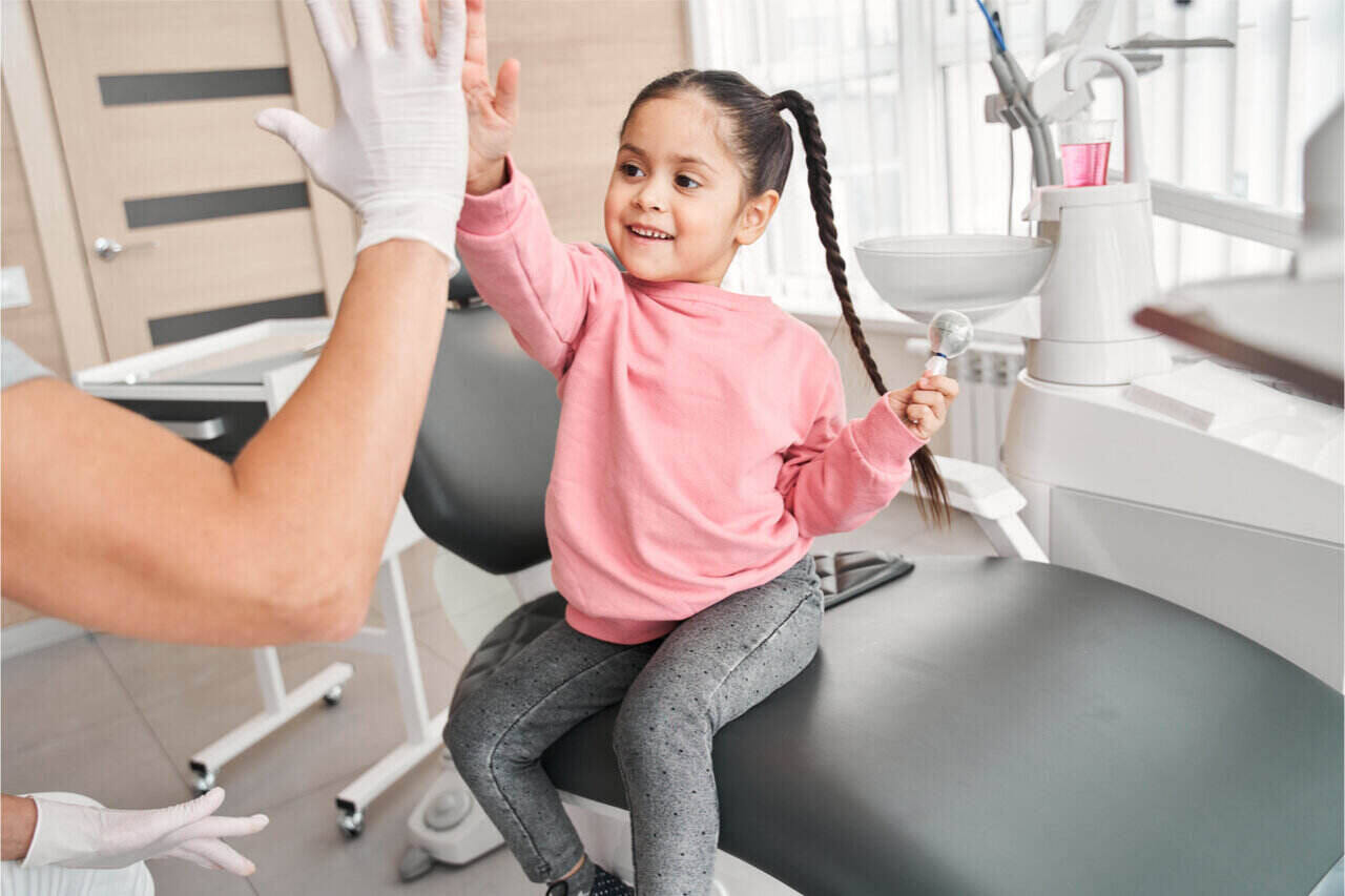 little girl gave her dentist a high-five after a tooth extraction